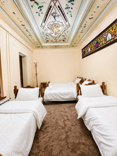two beds in a room with a ceiling at Shahina in Samarkand