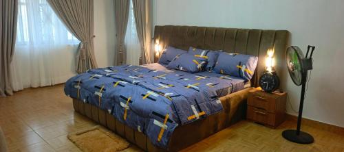 ein Schlafzimmer mit einem Bett mit einer blauen Bettdecke und einer Lampe in der Unterkunft Harlington Duplex in Akitan