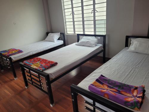a group of three beds in a room at Aama Ghar Siliguri in Siliguri