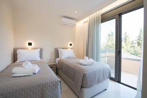 two beds in a room with a window at Glamour Residences 5-6 by CorfuEscapes in Análipsis