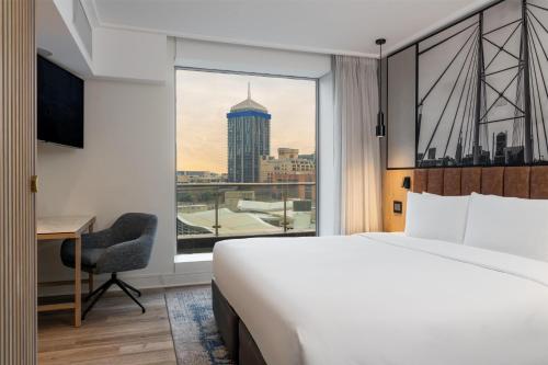 a hotel room with a large bed and a window at Radisson Blu Gautrain Hotel, Sandton Johannesburg in Johannesburg