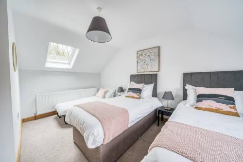 two beds in a bedroom with white walls at Luxury Cottage in the New Forest with Log Burner in Redlynch