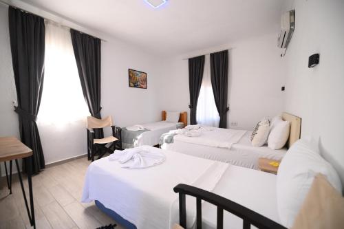 a hotel room with three beds and a table at Rijeka Pansiyon in Ayvalık
