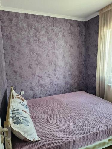 a bedroom with a bed with a purple wall at Paradise Mtskheta in Tbilisi City