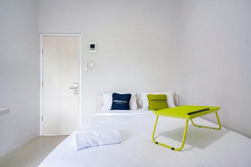 a white bedroom with a yellow table on a bed at Urbanview Hotel Bari Syariah Palembang By RedDoorz in Sukarami