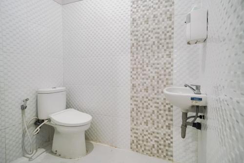 a white bathroom with a toilet and a sink at Urbanview Hotel Bari Syariah Palembang By RedDoorz in Sukarami