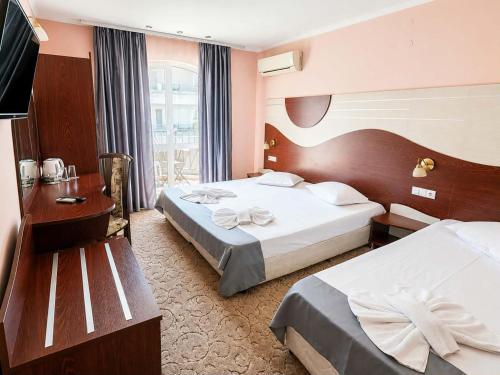 a hotel room with two beds and a desk at Palma in Burgas