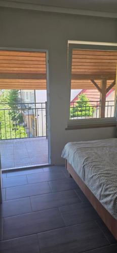 a bedroom with two windows and a bed and a balcony at Promyk 2 in Rewal