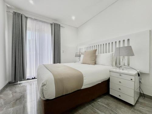a white bedroom with a large bed and a window at Number 12, Jadde apartments in Sandton