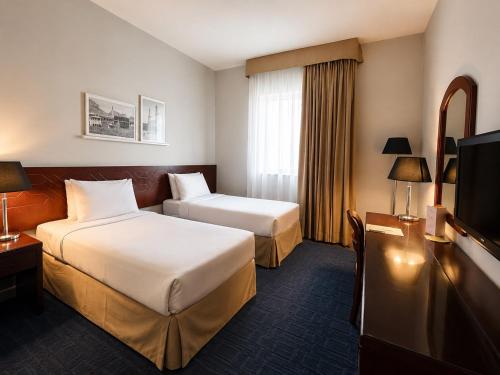 a hotel room with two beds and a television at Makarem Al Bait Al Azizia Hotel in Mecca