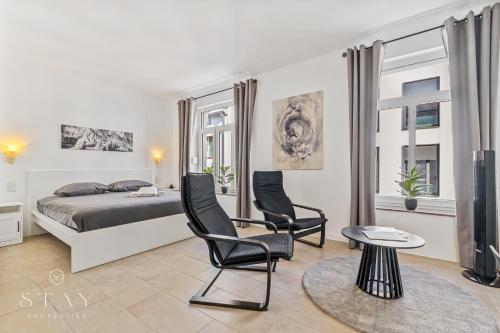 a bedroom with a bed and two chairs and a table at Hotel Stay Properties in Luxembourg