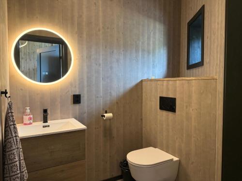 a bathroom with a sink and a toilet and a mirror at Flakstad beach house Silo A in Vareid