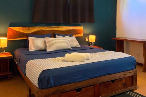 a bedroom with a large bed with blue sheets and pillows at Zipolite Maracuya Hostel & Rooms in Zipolite