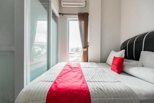 a bedroom with a red and white bed with a window at RedDoorz Plus near Palembang Airport 3 in Palembang