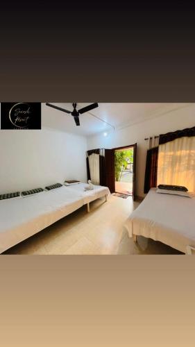 a bedroom with two beds and a ceiling fan at Saiesh resort in Alibaug