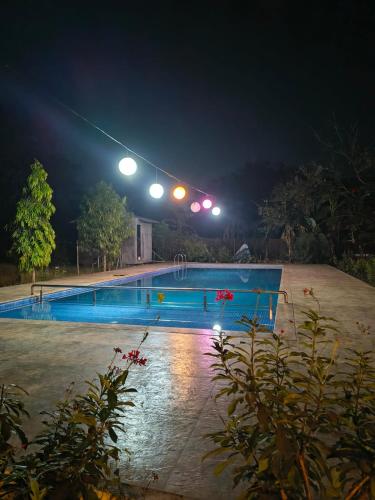 a swimming pool at night with lights above it at Saiesh resort in Alibaug