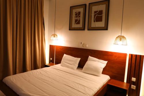 a bedroom with a bed with two pillows and two lights at Dream Assinie V in Mafia