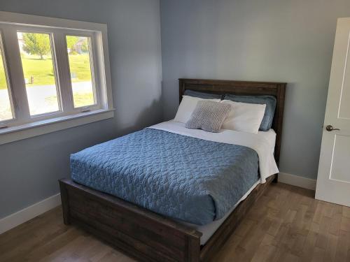 a bed in a bedroom with two windows at Quarto Gananoque #1 in Gananoque