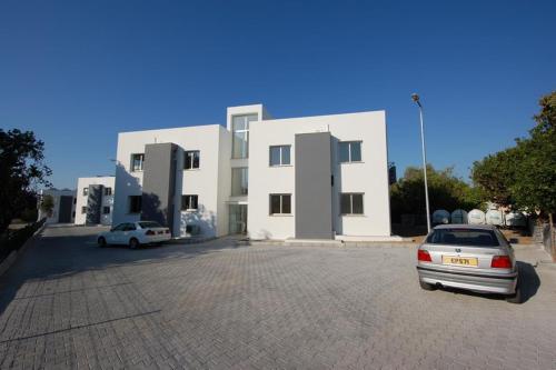une voiture garée devant un bâtiment blanc dans l'établissement Sun Rise Suit, à Kyrenia