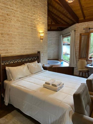 a bedroom with a large bed with towels on it at Chalés Montanha Serrana - Monte Verde in Monte Verde