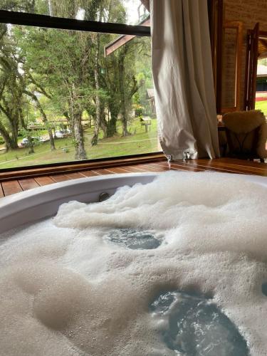 a bath tub filled with snow in front of a window at Chalés Montanha Serrana - Monte Verde in Monte Verde