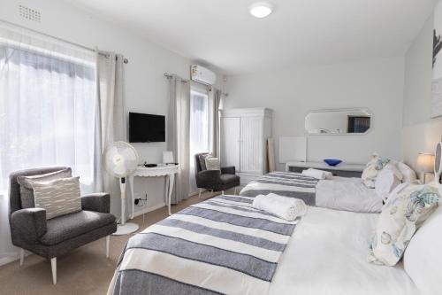a bedroom with two beds and two chairs and a television at Alfred View in Port Alfred
