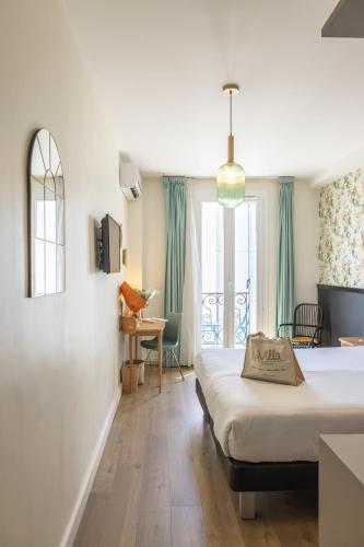 a hotel room with two beds and a table and chairs at Hotel La Villa Nice Promenade in Nice