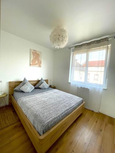 a bedroom with a bed and a window and a chandelier at Trois Merlettes in Schiltigheim