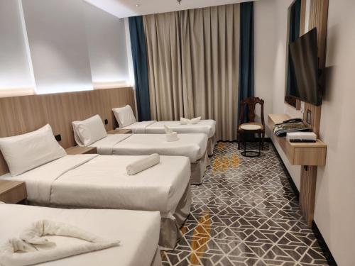 a hotel room with four beds and a flat screen tv at فندق بشاير الإجابة Bashaier Al EJaba Hotel in Mecca