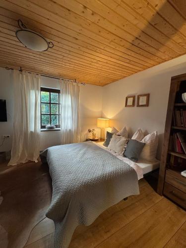 a bedroom with a white bed with a wooden ceiling at GENUSSZEIT Cottage in Udenhain