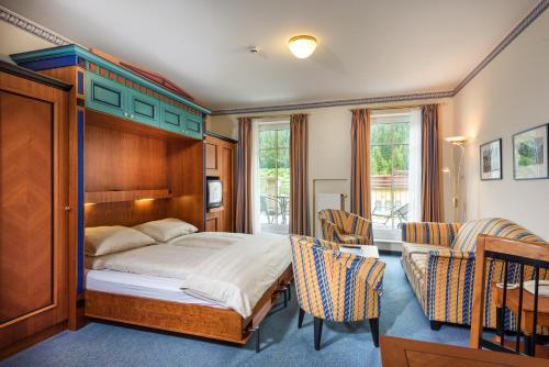 a bedroom with a bed with a wooden headboard and chairs at MONDI Hotel Bellevue Gastein in Bad Gastein