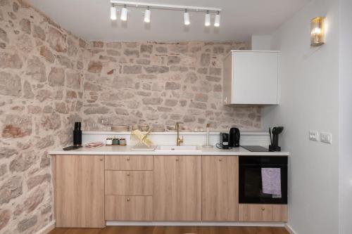 a kitchen with a sink and a stone wall at Sizgoric Palace Suites Sibenik in Šibenik