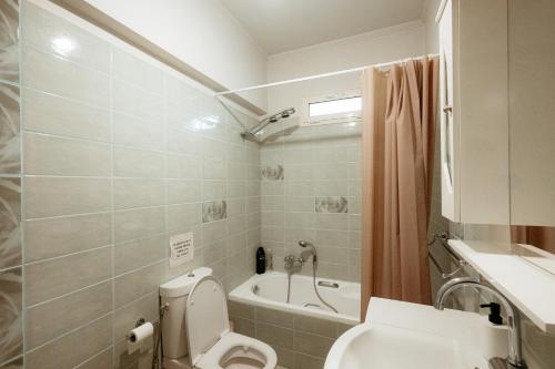 a bathroom with a toilet and a bath tub at Boomerang Villa in Patra