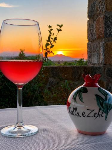 a glass of wine sitting on a table with a vase at Kulla Zefit Agritourism in Hajmel