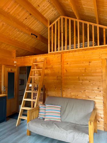 a loft bed in a wooden cabin with a couch at Greenwood Chalet in Ottershaw