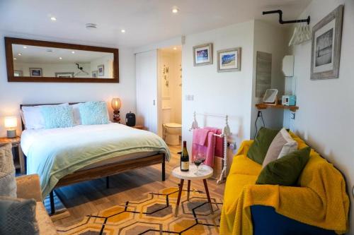 a bedroom with a bed and a couch and a mirror at Studio room with amazing views in Abersoch