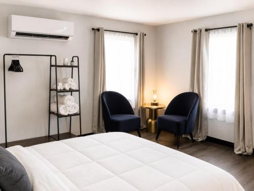 a bedroom with two chairs and a bed and windows at Spacious Private Queen Studio Near Downtown in Muskegon