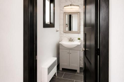 a white bathroom with a sink and a mirror at Spacious Private Queen Studio Near Downtown in Muskegon