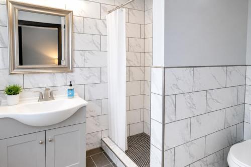 a white bathroom with a sink and a shower at Cozy Updated Queen Ground Floor Studio in Muskegon
