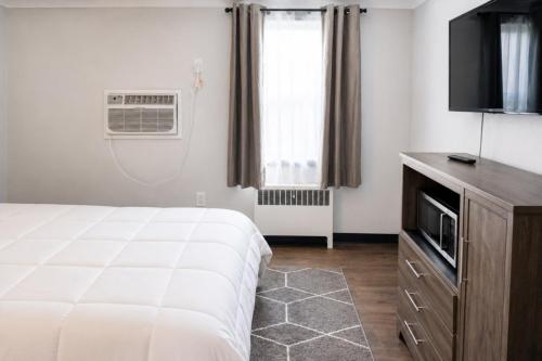 a bedroom with a bed and a tv and a window at Cozy Updated Queen Ground Floor Studio in Muskegon