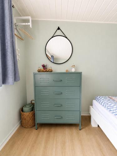 a bedroom with a green dresser and a mirror at Finnenhaus 8 in Lübeck