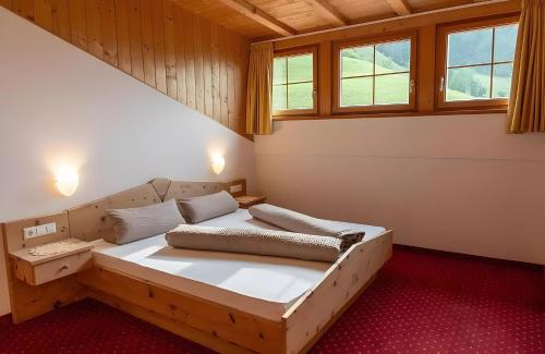 a bedroom with a bed in a room with windows at Ferienhof Blaas in Malles Venosta