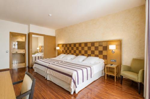 ein Hotelzimmer mit einem großen Bett und einem Stuhl in der Unterkunft Hotel Duran in Figueres