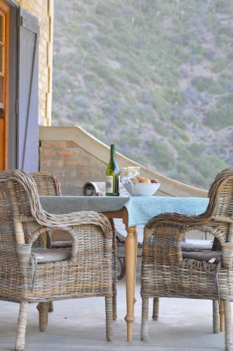 a table with a bottle of wine and two chairs at Schuilhoek Cottage - Your perfect hide away! in Calitzdorp