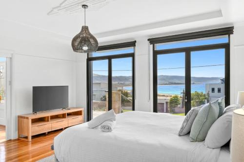a white bedroom with a large bed and a television at Marram House - Views in Marengo in Marengo