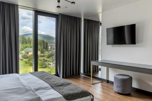 a bedroom with a bed and a desk and a large window at ETERNA HOTEL & SPA by Fomich in Palyanytsya
