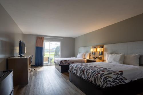 a hotel room with two beds and a flat screen tv at Colonial Brick Inn & Suites in New Milford