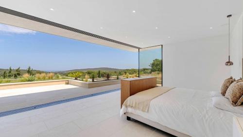 a bedroom with a bed and a large glass window at Villa Trois-Pins in Ramatuelle