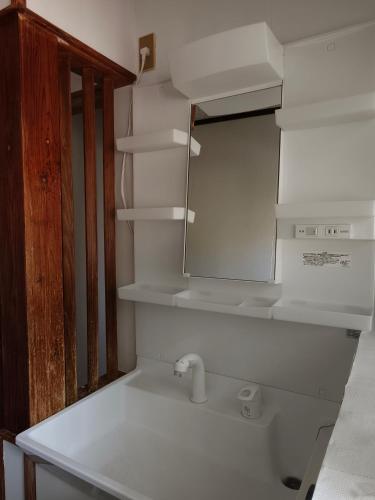 a white kitchen with a sink and a mirror at Ikada in Amami