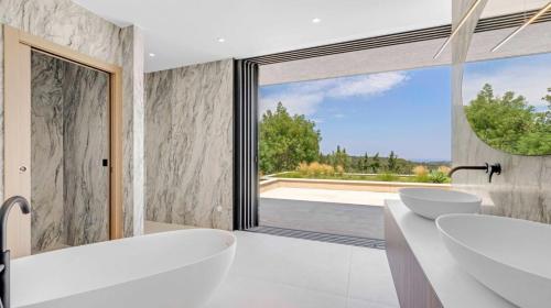 a bathroom with two sinks and a large window at Villa Trois-Pins in Ramatuelle